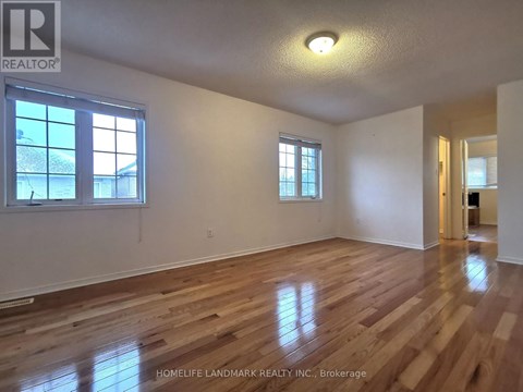 A room with wooden floors and two windows.