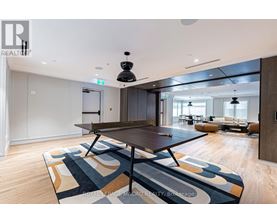 A modern dining room with a large table and a rug with a geometric pattern.