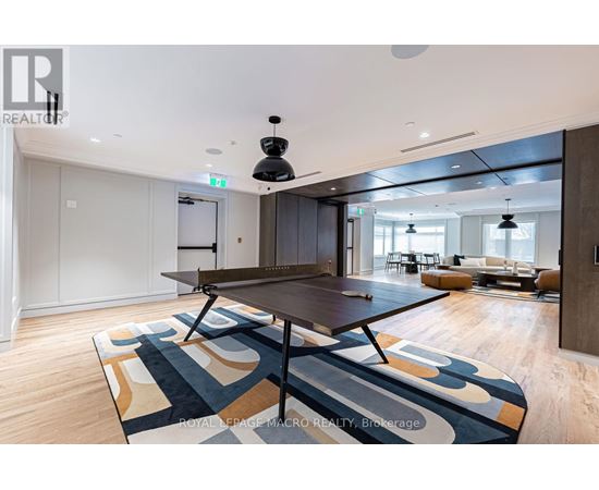 A modern dining room with a large table and a rug with a geometric pattern.