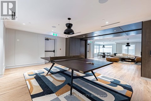A modern dining room with a large table and a rug with a geometric pattern.