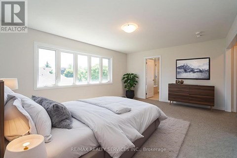 A bedroom with a large bed and a view of trees outside the window.