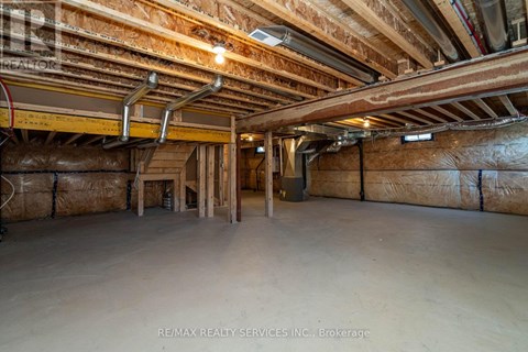 A spacious unfinished room with exposed ceiling beams and insulation on the walls.