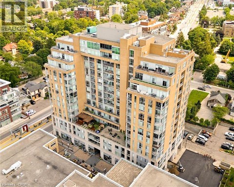 A tall building with a lot of windows and balconies is surrounded by trees and other buildings.