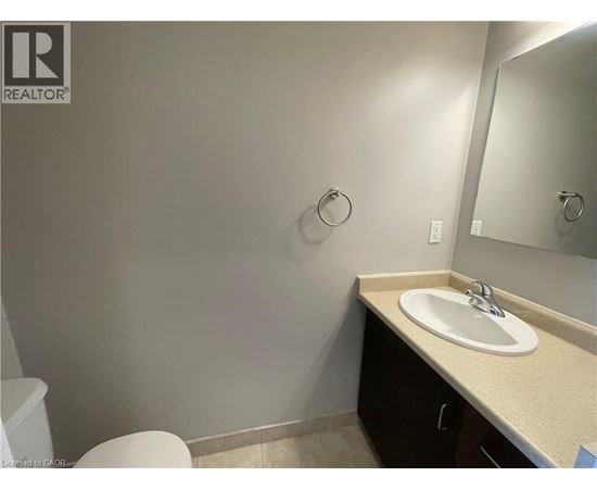 A bathroom with a toilet, sink, and mirror.