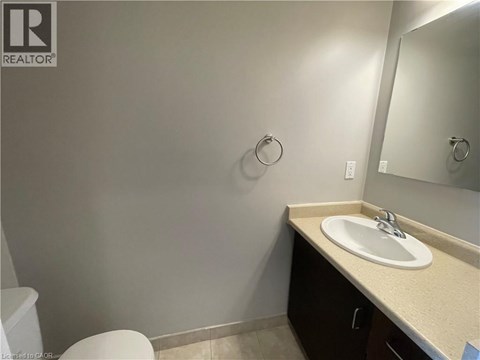 A bathroom with a toilet, sink, and mirror.