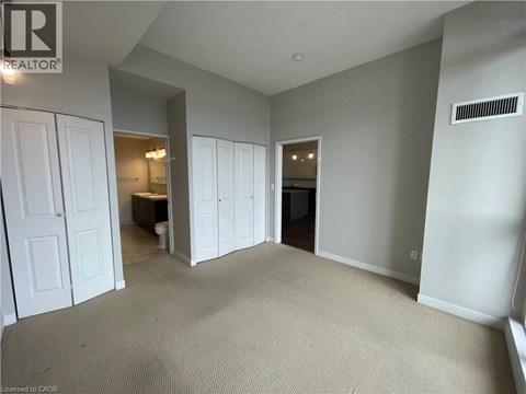 A spacious room with a carpeted floor and white walls.
