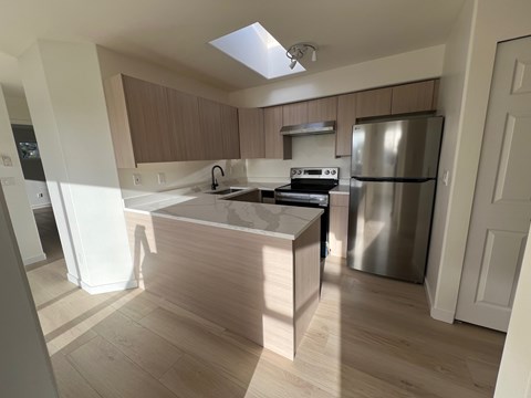 A kitchen with a stainless steel refrigerator and wooden cabinets.