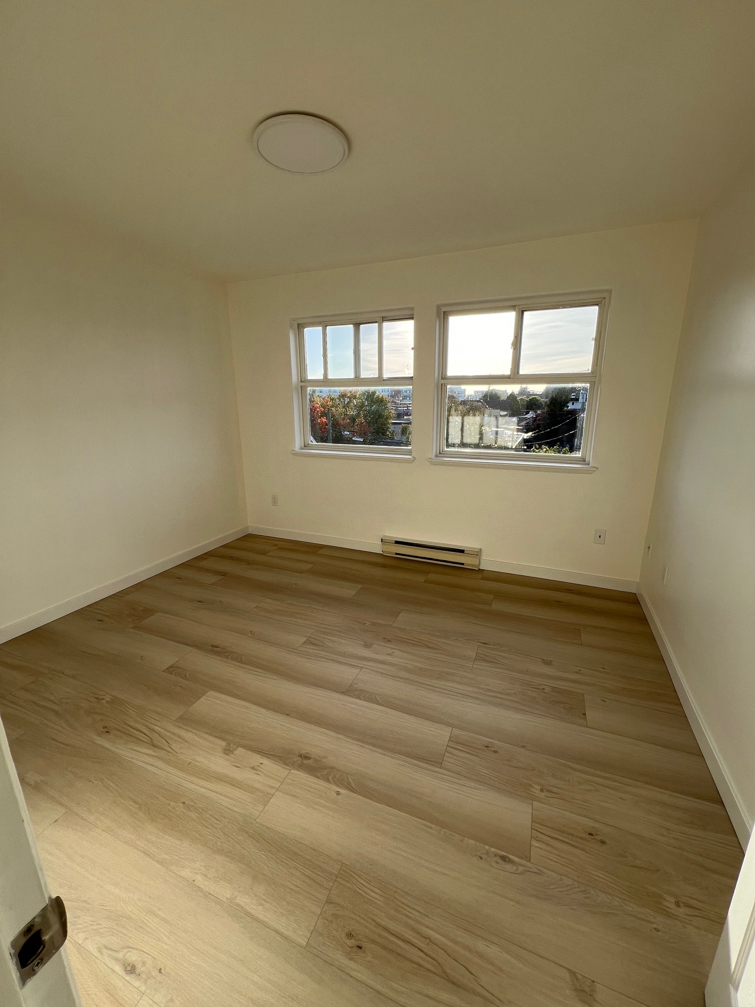 A room with a window and a wooden floor.