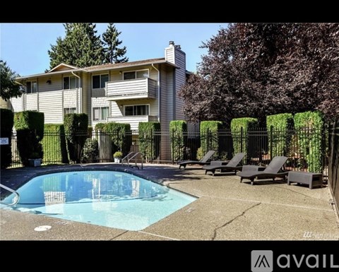 A pool surrounded by lounge chairs and a building in the background.
