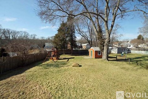 A backyard with a swing set and a small shed.