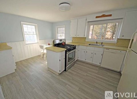 A kitchen with white cabinets and a wooden floor.
