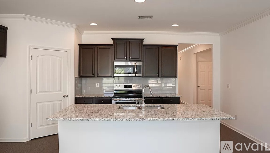 A kitchen with a white countertop and dark brown cabinets.