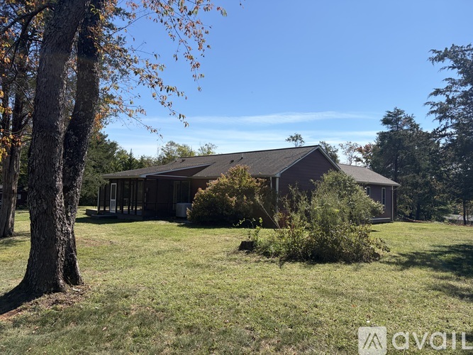 A house with a brown roof is surrounded by trees and grass.