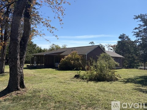 A house with a brown roof is surrounded by trees and grass.