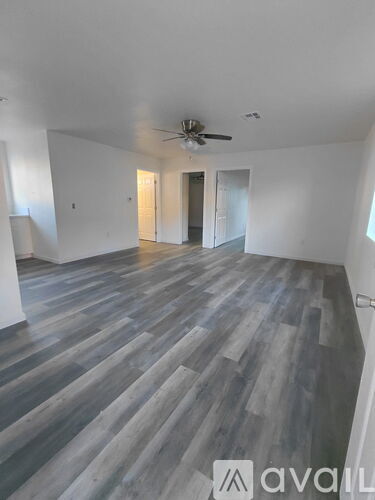 A spacious room with wooden flooring and a ceiling fan.
