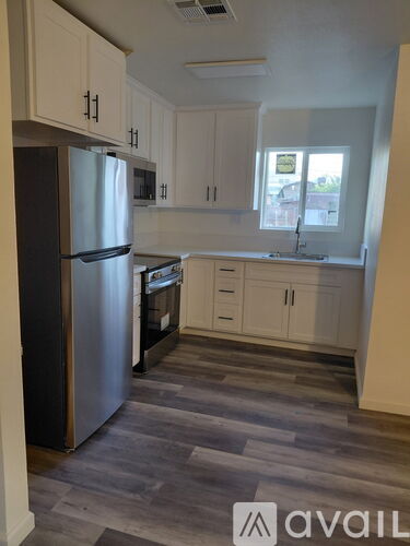 A kitchen with a refrigerator, cabinets, and a sink.