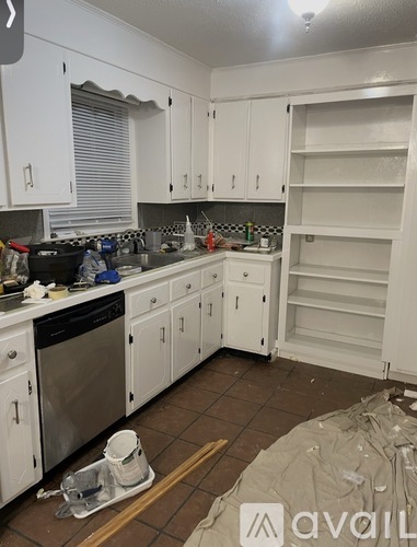 A kitchen with white cabinets and appliances is under renovation.