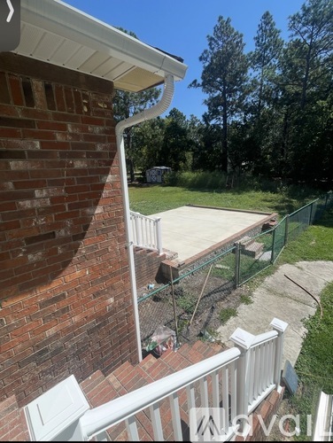A white railing is on the left side of a brick building.