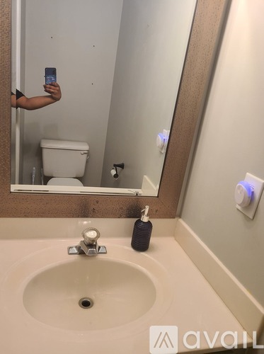 A person is taking a selfie in a bathroom with a white sink and a mirror.