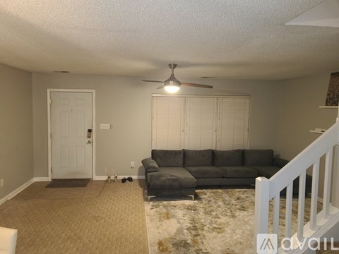 A living room with a grey couch and a ceiling fan.