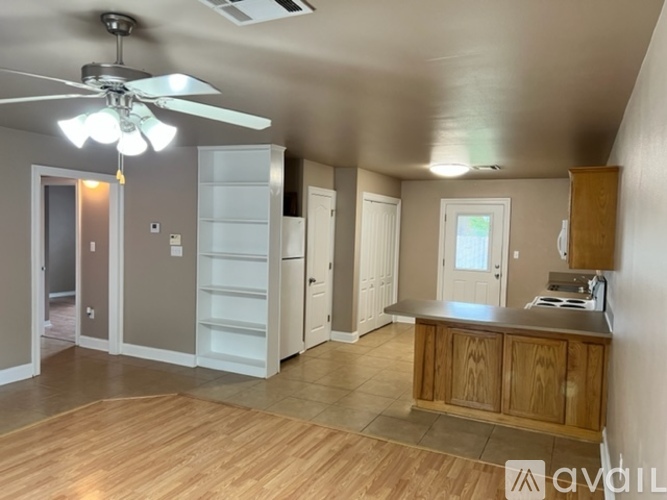 A kitchen with a fan and wooden floors.
