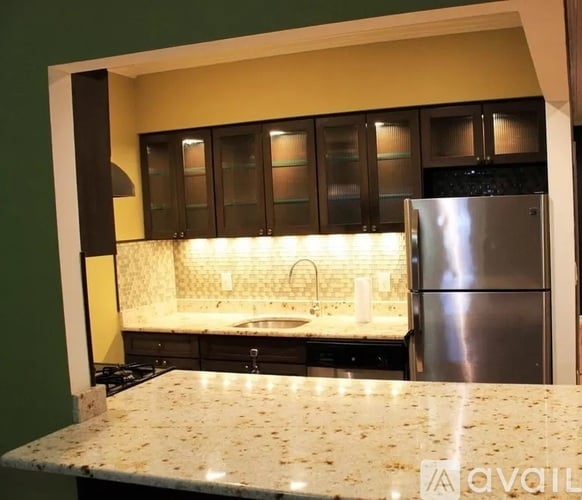 A kitchen with granite countertops and a stainless steel refrigerator.