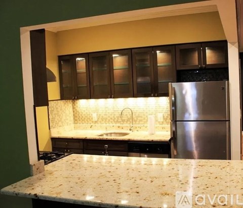 A kitchen with granite countertops and a stainless steel refrigerator.