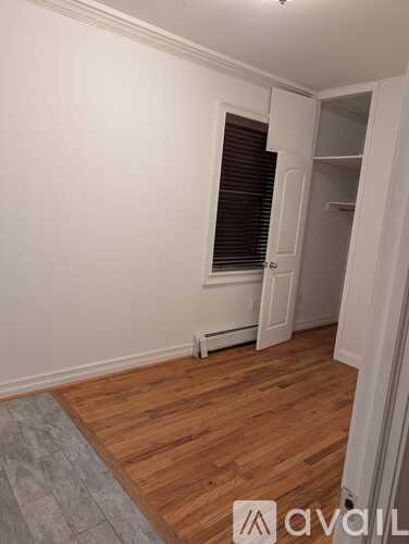 A room with wooden flooring and a window with blinds.