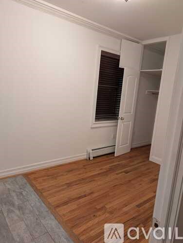 A room with wooden flooring and a window with blinds.