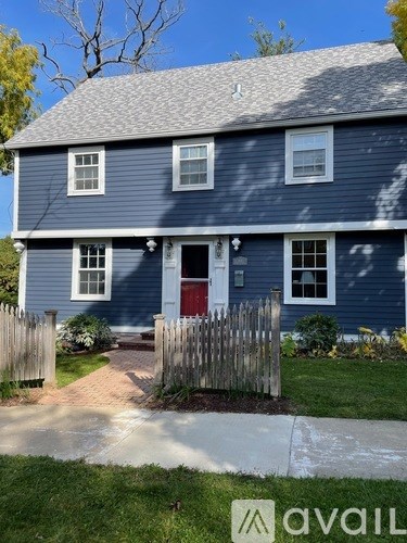 A blue house with a red door and a wooden fence.