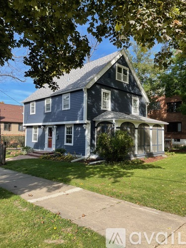 A blue house with white trim and a red door.