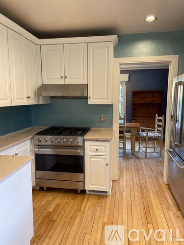 A kitchen with white cabinets and a wooden floor.
