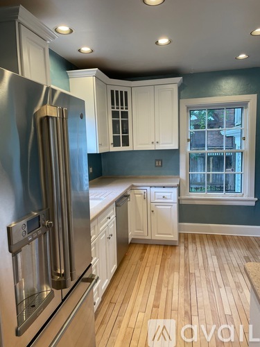 A kitchen with a stainless steel refrigerator and wooden floors.