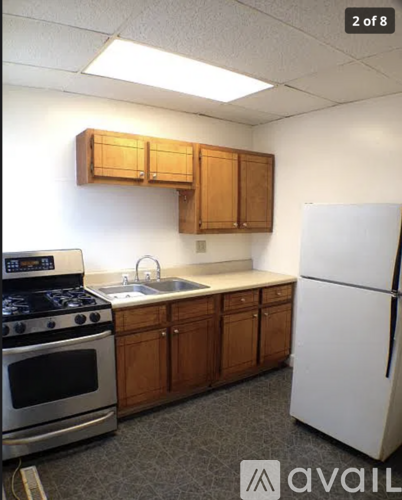 A kitchen with a white refrigerator, a stove, and wooden cabinets.