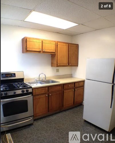 A kitchen with a white refrigerator, a stove, and wooden cabinets.