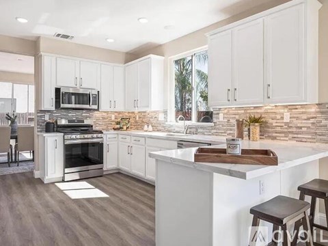 A kitchen with white cabinets and a stone backsplash.