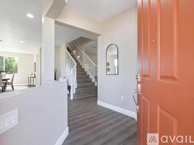 A hallway with a staircase and a red door.
