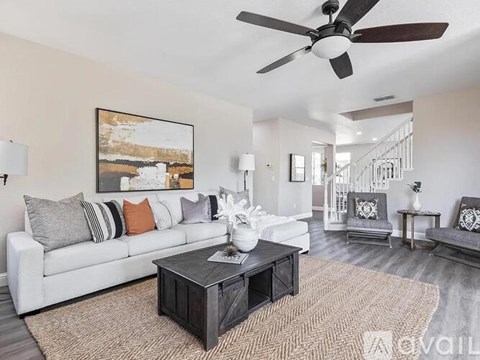 A living room with a white couch, a coffee table, and a painting on the wall.