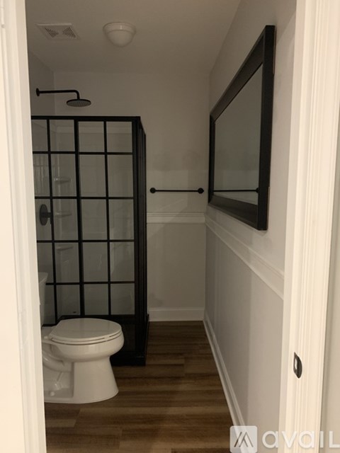 A white toilet sits in a bathroom with a glass shower door.