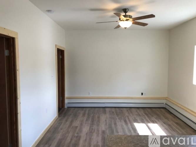 A room with a ceiling fan and wooden flooring.