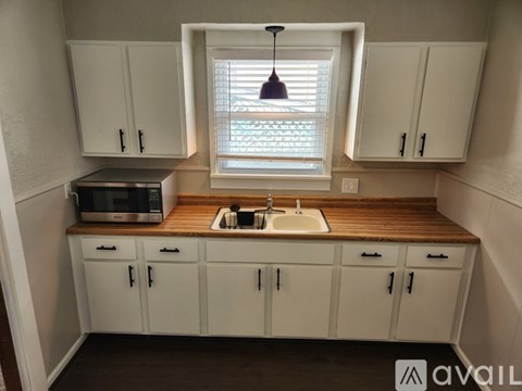 A kitchen with white cabinets and a wooden countertop.