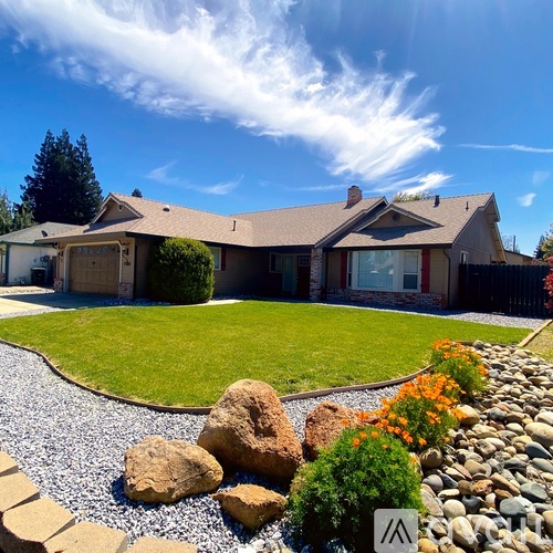 A house with a brown roof and a gravel garden in front.