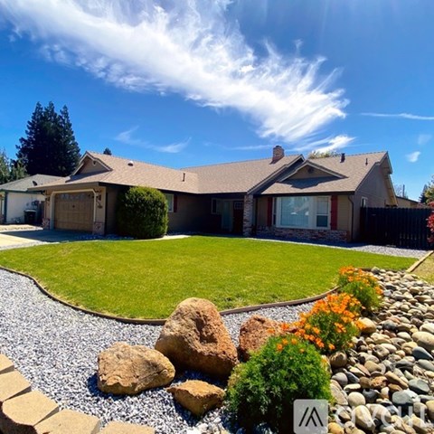 A house with a brown roof and a gravel garden in front.