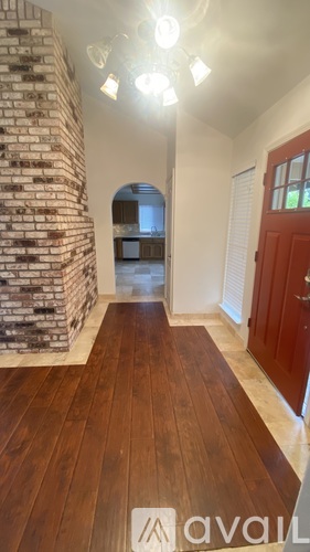 A hallway with wooden floors and a brick wall.