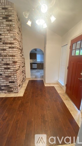 A hallway with wooden floors and a brick wall.