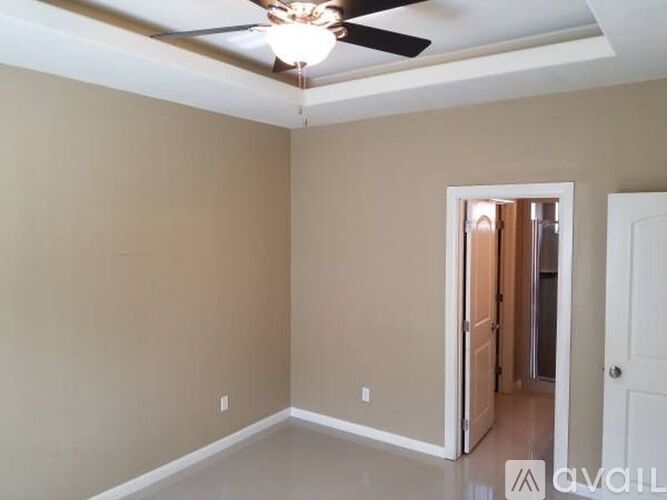 A room with a ceiling fan and a doorway leading to another room.