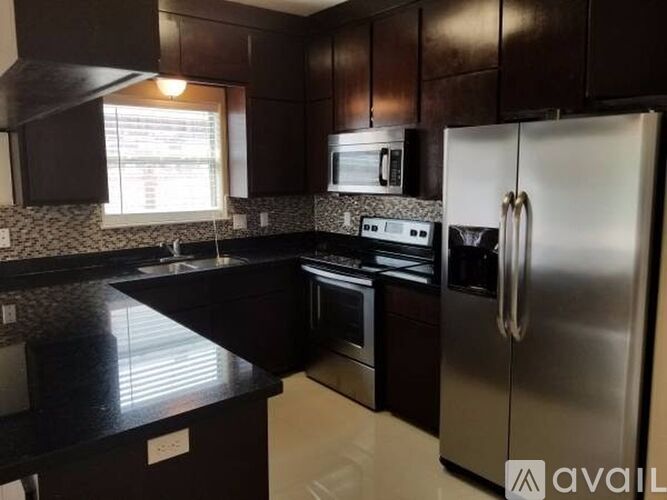 A kitchen with black countertops and stainless steel appliances.