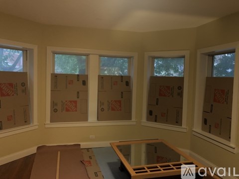 A room with three windows covered in cardboard boxes.