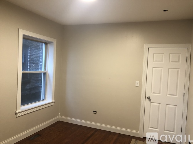 A room with a white door and a window with a view of a building outside.