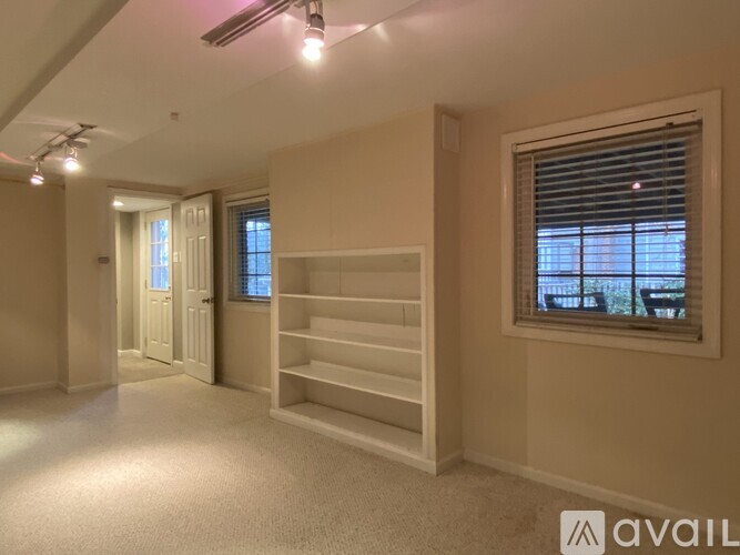 A spacious room with a window and a carpeted floor.